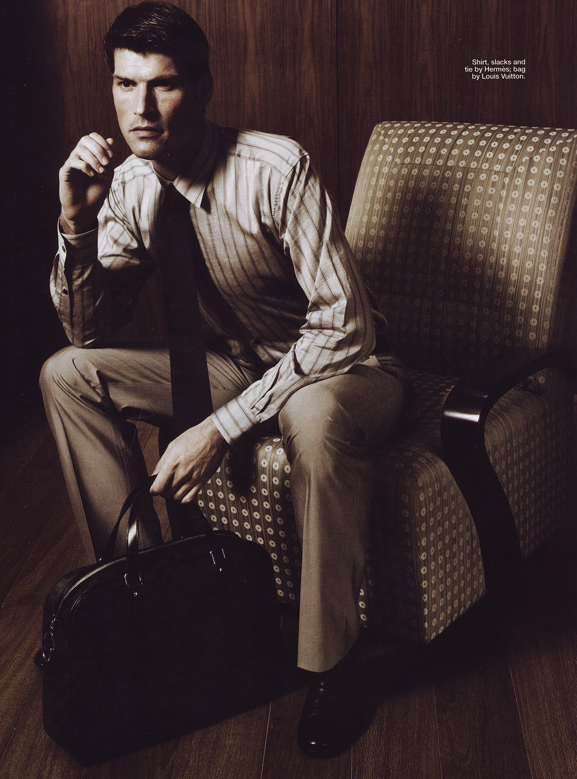 Fashion editorial: seated figure in a striped shirt and tie.